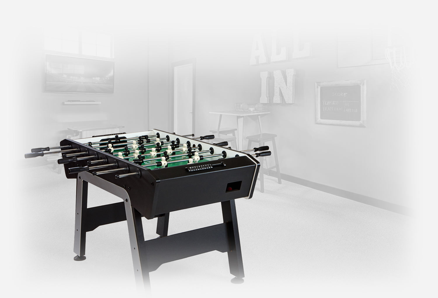 Foosball table in mostly black with silver and white accents in a rec room that is colored in faded grey tones
